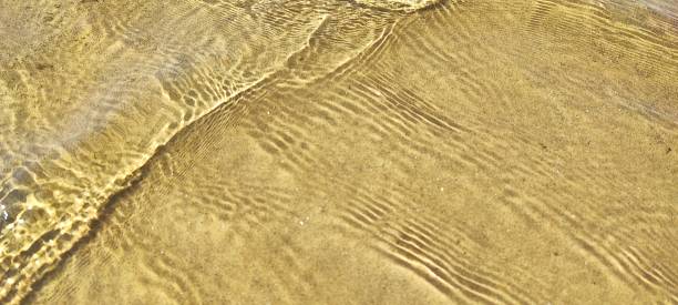 istock Small waves, ripples on the surface of water, with sand underneath. 2177931320