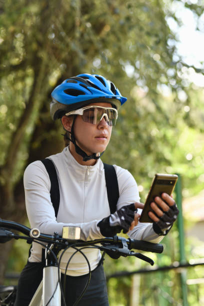 istock Female Biker Dressed in Professional Biking Clothes Tracking Biking Route on Mobile Device While Taking Break and Leaning on Bike 2177934289