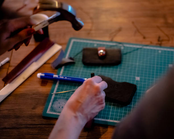 istock Female hand working on the leather wallet in his workshop 2177935276