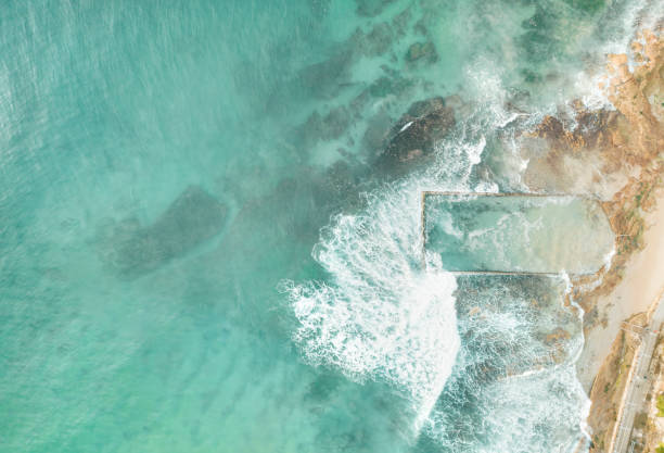 istock Waves crash over the ocean rock pool aerial view 2177940125