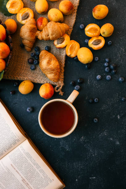 Cup of tea, open book, apricots and blueberries, summer mood