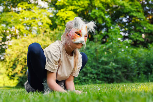 Cute young little kid girl wear cat furry mask enjoy have fun playing outdoors in forest street park. Children therian wild animal character trendy fan culture. Teenager social expression hobby. linda niña pequeña usa máscara peluda de gato, disfruta divirtírate jugando al aire libre en el parque de la calle del bosque. personajes de animales salvajes de moda para niños, cultura de fans de moda. pasatiempo de expresión social adolescente