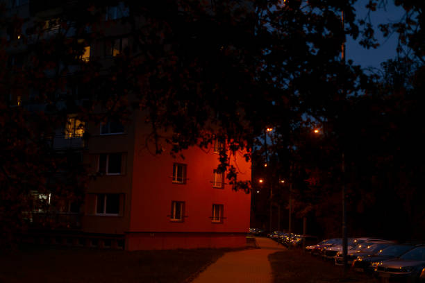 A vibrant red building adorned with numerous windows is beautifully illuminated at night, casting a warm glow in the evening environment