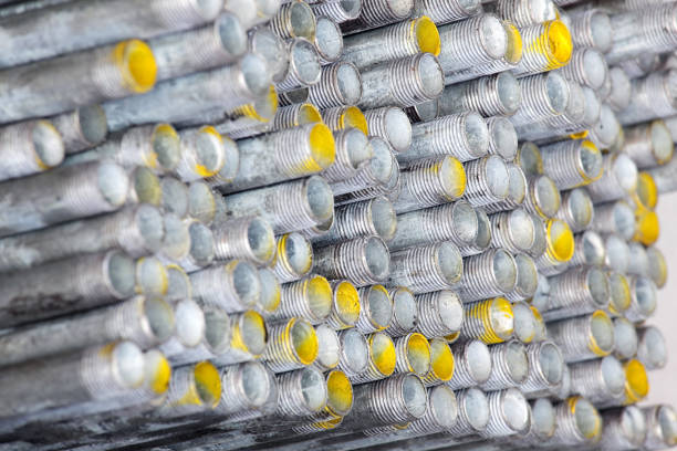Close-up view of stacked metal pipes featuring threaded ends and bright yellow paint highlights. Ideal for industrial and construction themes.