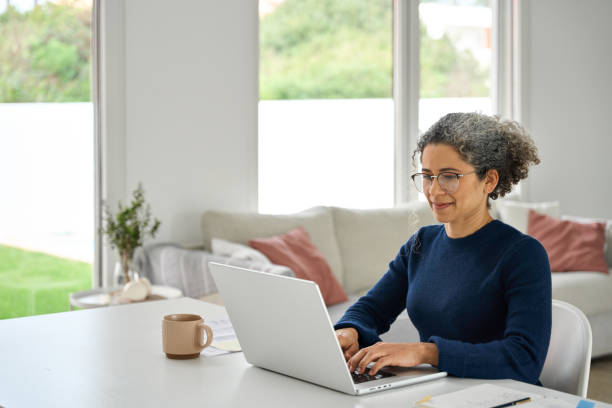 istock Happy middle aged woman sitting at table and using laptop in modern house. 2177949708