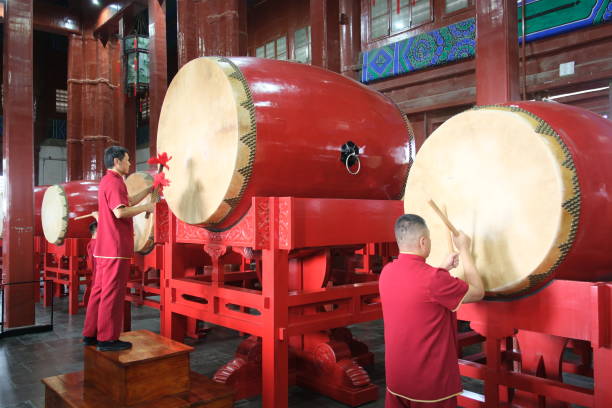Hong Kong - April 02, 2023: a chinese woman playing a drum at Yeung Hau Temple, a Chinese Folk temple in Tai O. The temple it is dedicated to Hau Wong who was a military general renowned for his loyalty. It is believed that he will protect devotees from evil spirits.