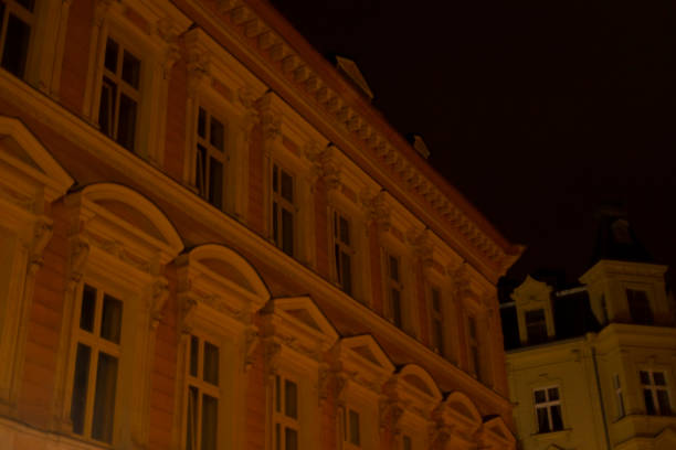 A large building, adorned with numerous bright windows, is beautifully illuminated during the night, creating a stunning display against the darkness