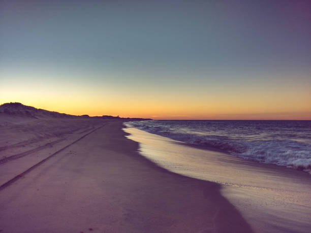 Sunset on the horizon and beach sand with tire tracks. São Miguel do Gostoso, Rio Grande do Norte, Brazil.