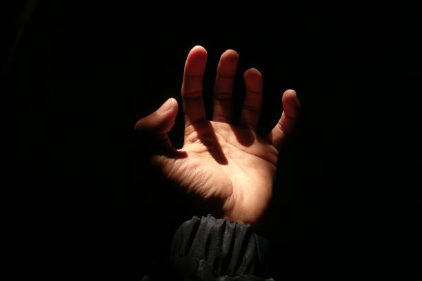 istock Male hand reaching for light in darkness on isolated black background. 2177954853