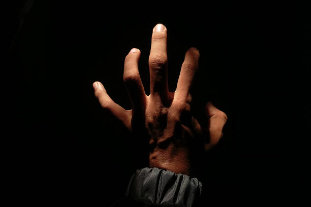 istock Male hand reaching for light in darkness on isolated black background. 2177954857