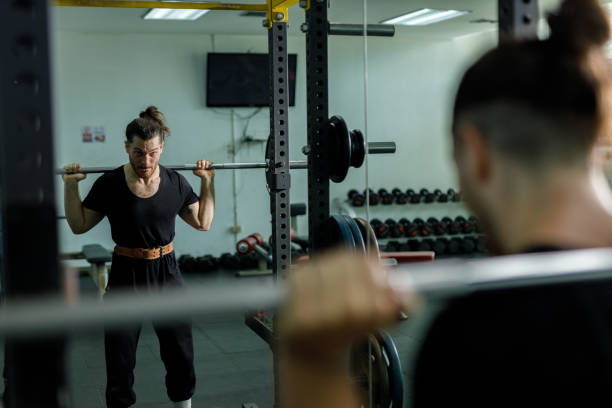istock muscular man is exercising and lifting weights exercise. Increase arm and shoulder muscles. weightlifting training in squat workout. 2177955281