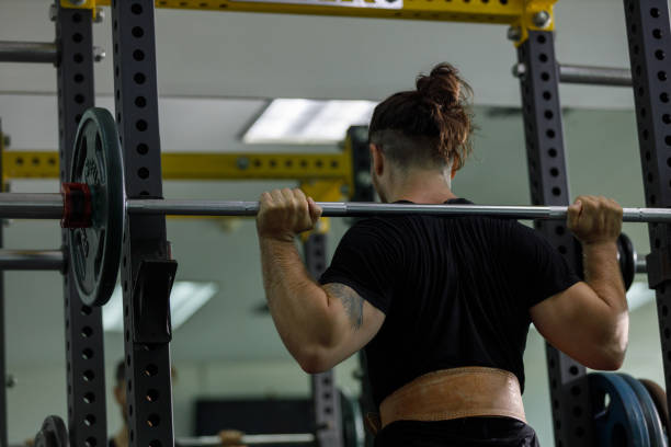 istock muscular man is exercising and lifting weights exercise. Increase arm and shoulder muscles. weightlifting training in squat workout. 2177955327