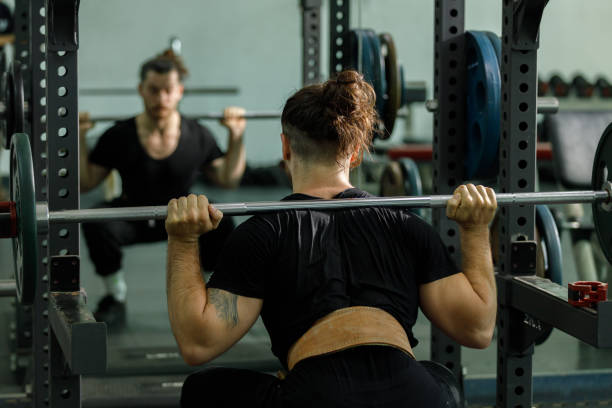 istock muscular man is exercising and lifting weights exercise. Increase arm and shoulder muscles. weightlifting training in squat workout. 2177955334
