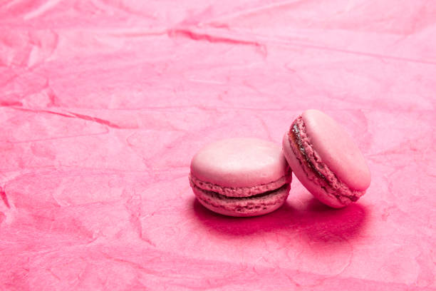 Raspberry flavor french macarons pastry on pink paper background