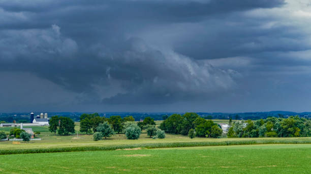 istock Dark Storm Clouds Loom Over Farmland With a Distant Barn and Trees Under an Ominous Sky 2177962129