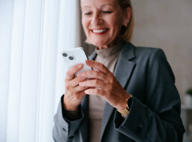 istock Elderly Woman Smiling While Using Smartphone at Home 2177969684