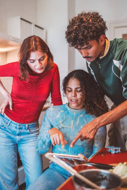 istock two young woman and young looking on digital tablet in kitchen 2177972065