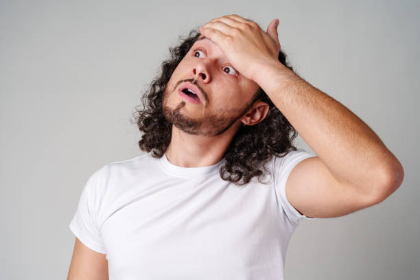 istock A man with curly hair expresses surprise while looking upwards in a neutral background 2177972628