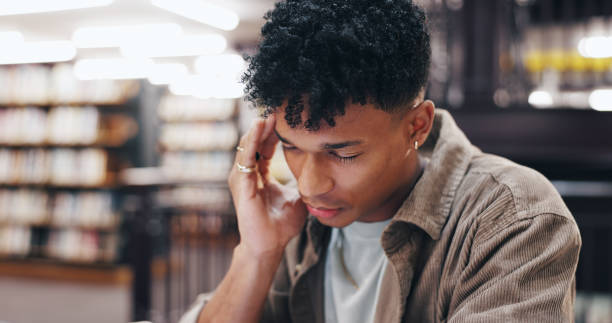 istock Headache, student and library with burnout, stress and deadline for university exam with pain. Fatigue, tired and tired from studying, learning and worry with financial debt and college fees 2177975195