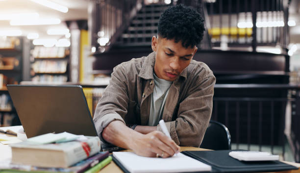 istock Writing, book and research with man in library for knowledge, education and college thesis. Learning, future and university with student and studying on campus for exam, project and scholarship 2177975200