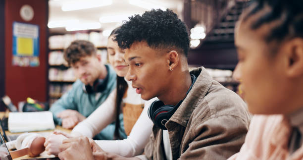 istock College, students and study group with laptop in library for exam preparation, homework assignment or research project. People, discussion and technology for learning, knowledge and scholarship test 2177975223