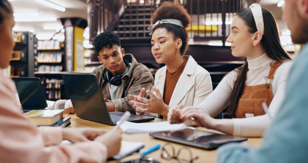 istock People, students and laptop in library for discussion, planning and working on research assignment. Study group, exam preparation or tech at university for education, collaboration or course feedback 2177975234