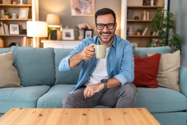 istock Handsome man sit on sofa and hold coffee look at the camera and smile 2177975733