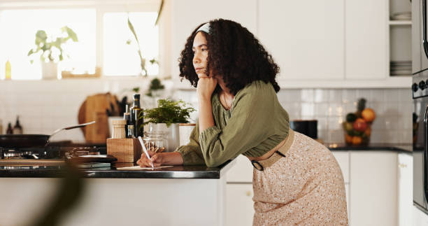 istock Cooking, kitchen and woman with notebook, ideas and planning for recipe, thinking or writing in home. Meal prep, morning and person with info for ingredients, contemplating or research of instruction 2177976329