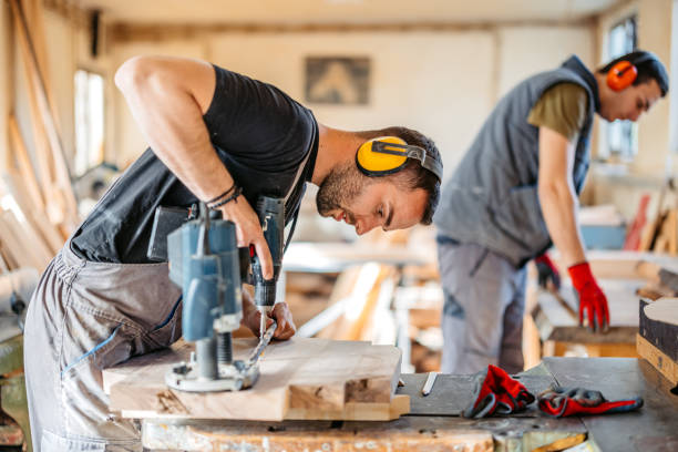 istock Young Male Carpenter Using An Electric Drill On The Wood In His Workshop 2177976735