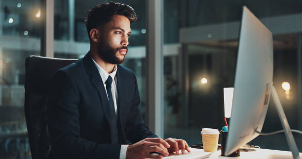 istock Computer, night and serious with business man at desk in office for administration or research. Information, reading and report with confident employee typing on PC for deadline or overtime at work 2177979109