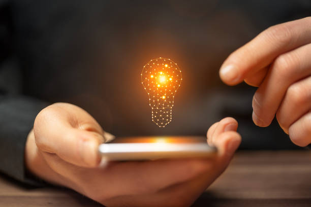 istock Idea concept with hand holding smartphone with glowing light bulb 2177980219