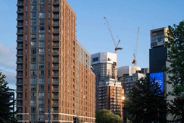 A view of modern high-rises and construction cranes in Leeds during the late afternoon. The cityscape captures a blend of completed structures and ongoing urban development against a clear blue sky.