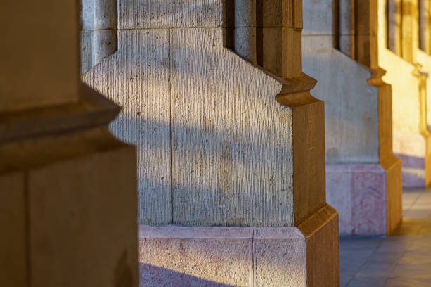 Base of repeated stone columns of old building, with shadows, in sunlight, telephoto