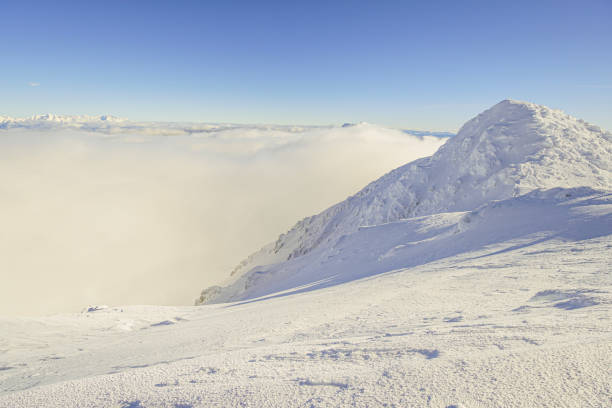 View of the snowy peak with cloud in the valley, sunny, winter, between mountains, Slovakia, Chopok, wide angle lens