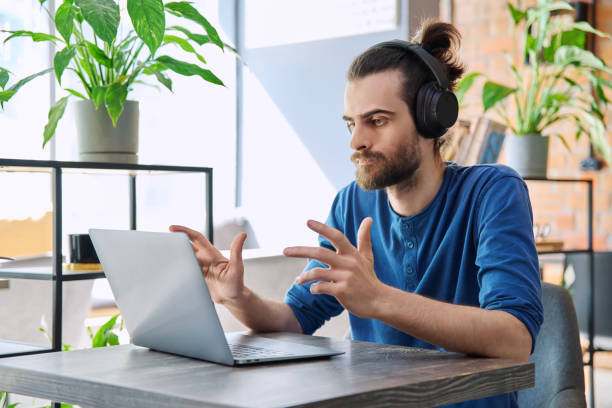 istock Young handsome man in headphones having work video chat using laptop 2177997197