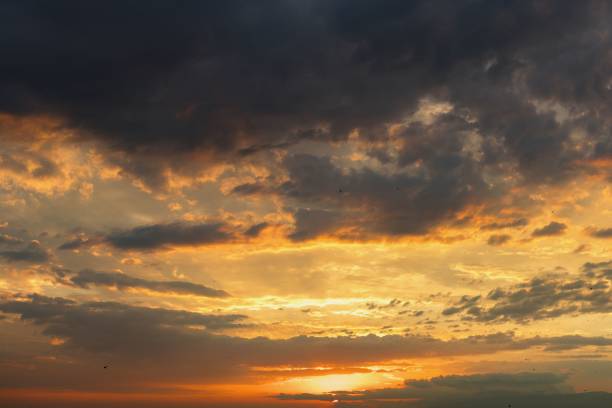 A dramatic sunset sky with vibrant orange and yellow hues beneath dark clouds