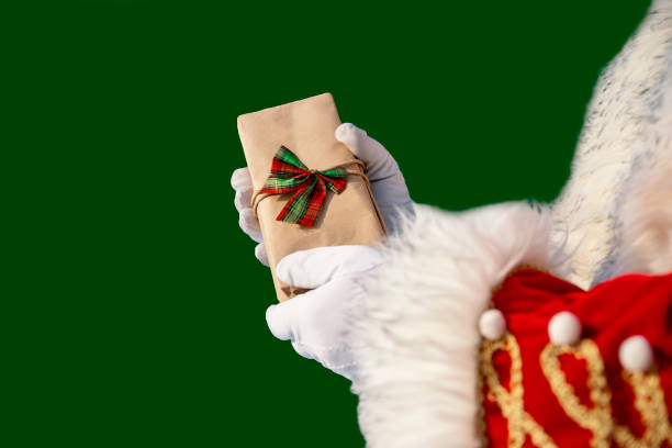 Santa hands with gift box on green background. Copy space