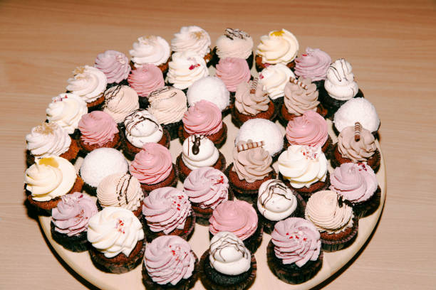 Assorted cupcakes on wooden plate with chocolate and cream frosting