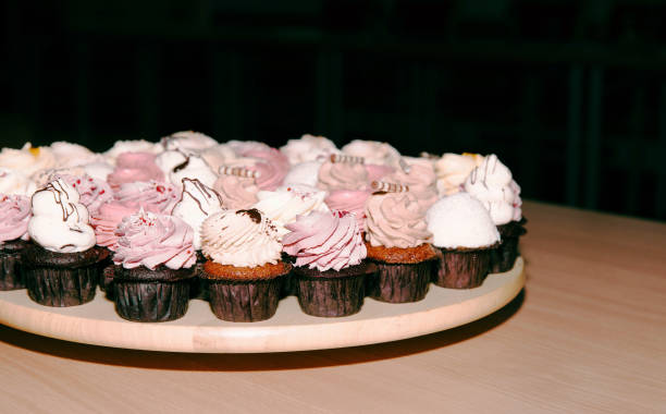 Assorted cupcakes on wooden plate with chocolate and cream frosting