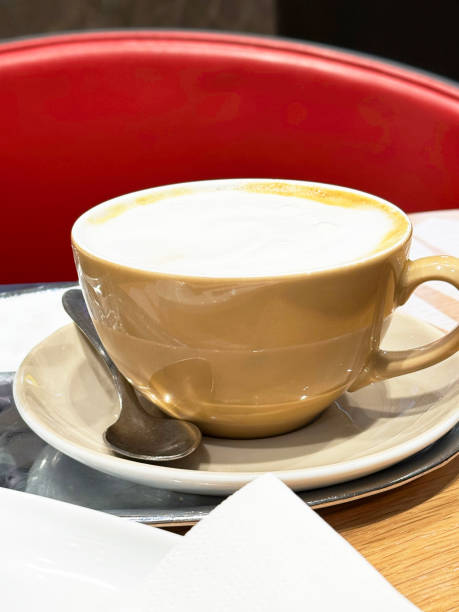 istock Warm cappuccino in beige cup on saucer with silver spoon in cozy cafe setting 2178003979