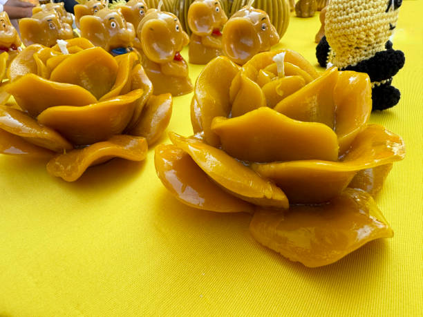 Handcrafted yellow beeswax rose candles with decorative figures on yellow tablecloth