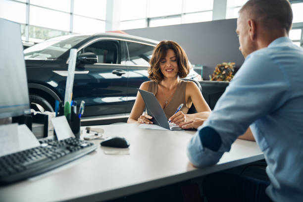 istock Young lady signing documents while buying new car 2178005031