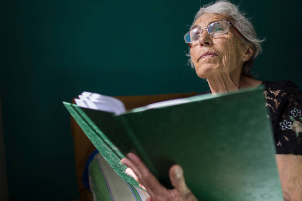 istock Elderly Woman Pensively Reading a Large Green Book 2178010178