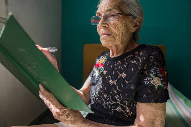 istock Elderly Woman Reading Document in Sunlit Room 2178010215