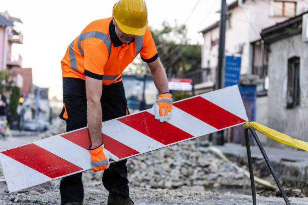istock Construction worker lifting a barrier on a road under repair in an urban area during daylight hours 2178014848