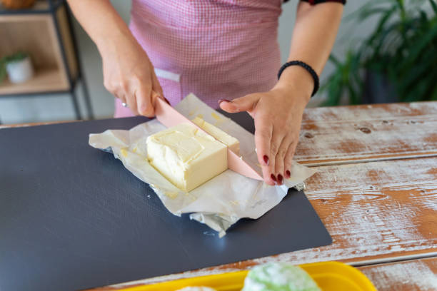 Woman Cutting Butter for Baking on Wooden Table