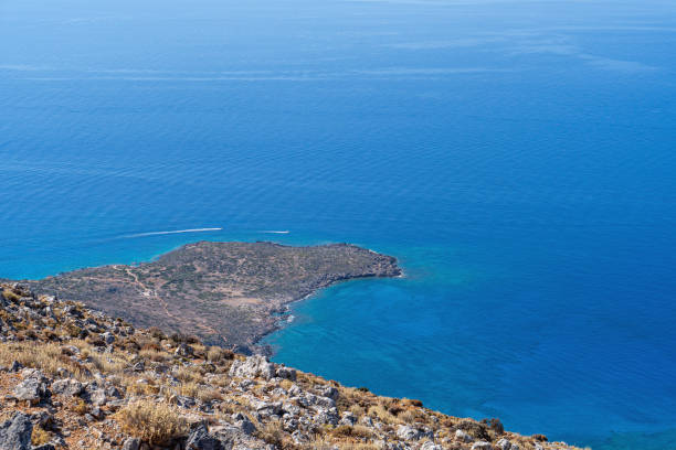 Rocky mountainside on the beach with calm blue sea water in the sun, landscape, Greece, island of Crete, telephoto