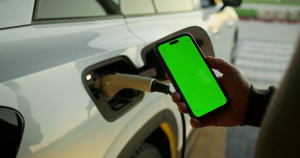 istock A man uses a mobile phone standing near an electric car 2178020003
