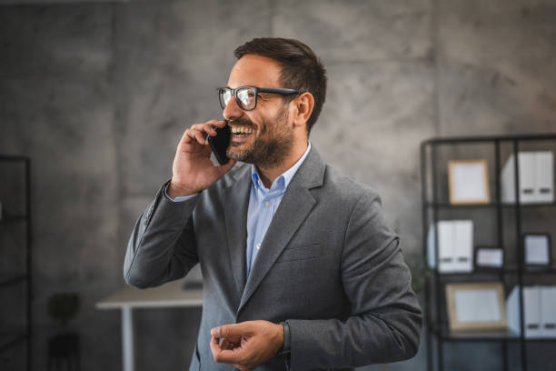 istock cheerful businessman talk on mobile phone and smile in modern office 2178021749