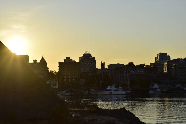 View of buildings across Victoria Harbour with sunrise on left side